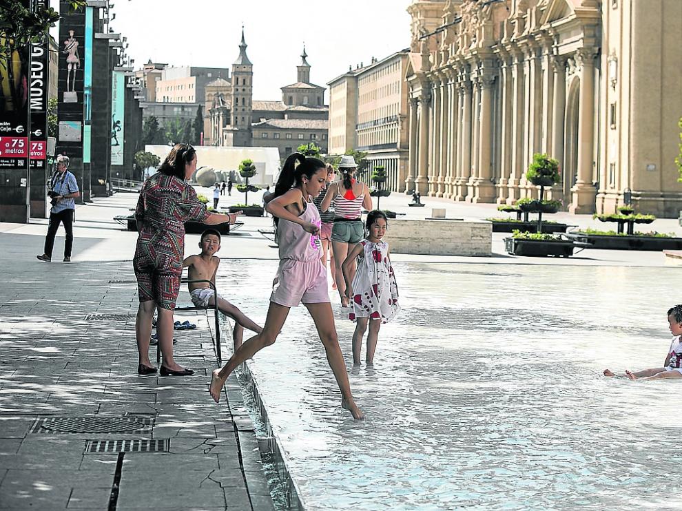 Varias personas se refrescan para combatir el calor, este martes en la fuente de Goya de Zaragoza.