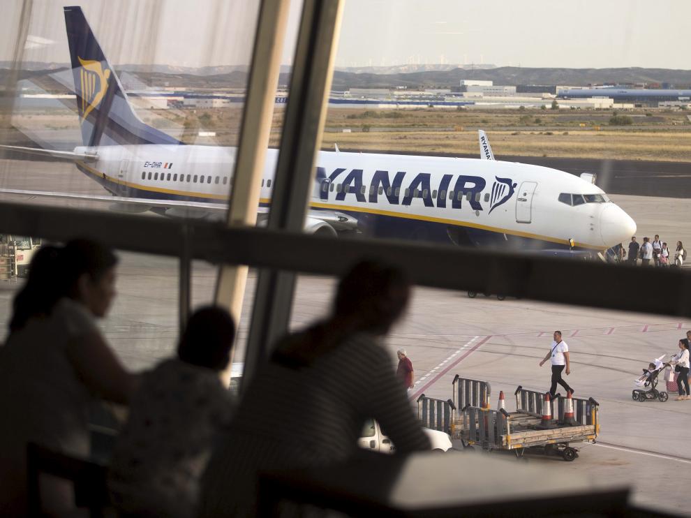 Un grupo de pasajeros observan un avión de Ryanair desde los ventanales del aeropuerto de Zaragoza.