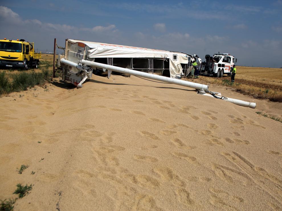 El camión ha volcando ocupando toda la calzada y ha perdido la carga de grano que transportaba.