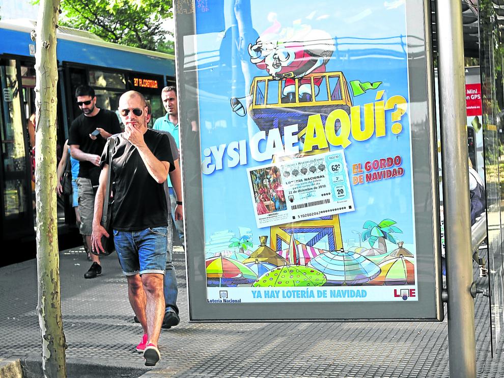 Cartel que anuncia el sorteo de Lotería de Navidad expuesto en una marquesina de autobús en pleno verano.