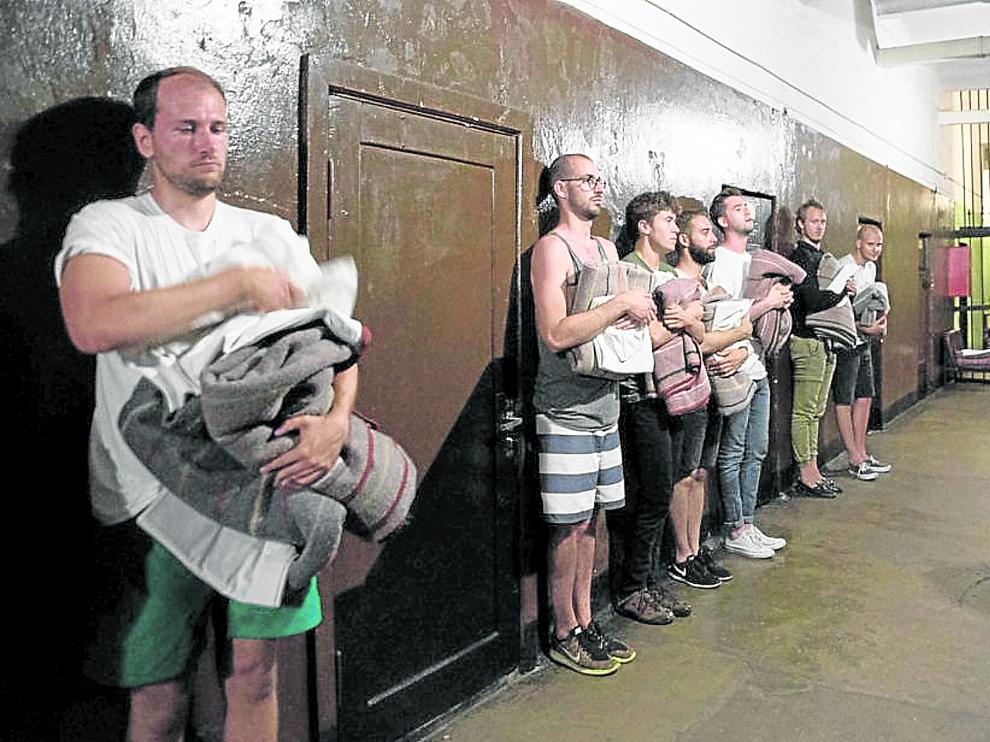 Unos turistas que se han atrevido a pasar la noche como reos son inspeccionados en la cárcel de Karosta por el oficial de turno.