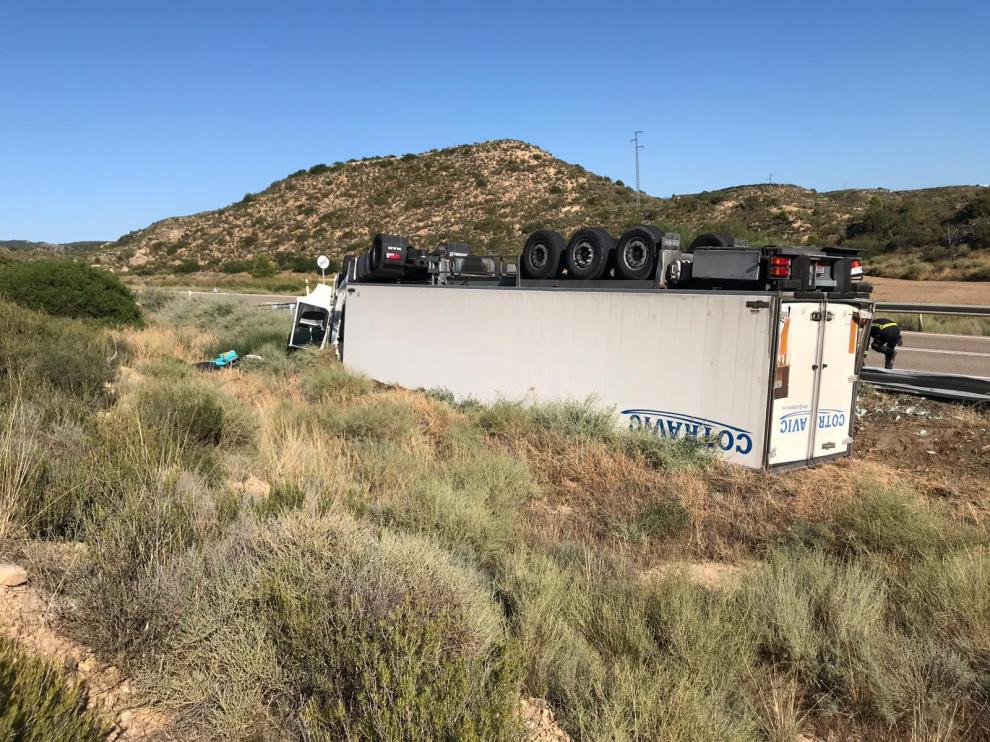 El camión ha quedado volcado en el arcén con las ruedas hacia arriba.