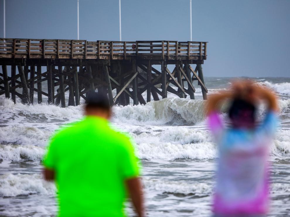 Unas personas contemplan la marea en la playa de Daytona, Florida, antes de la llegada del huracán Dorian.