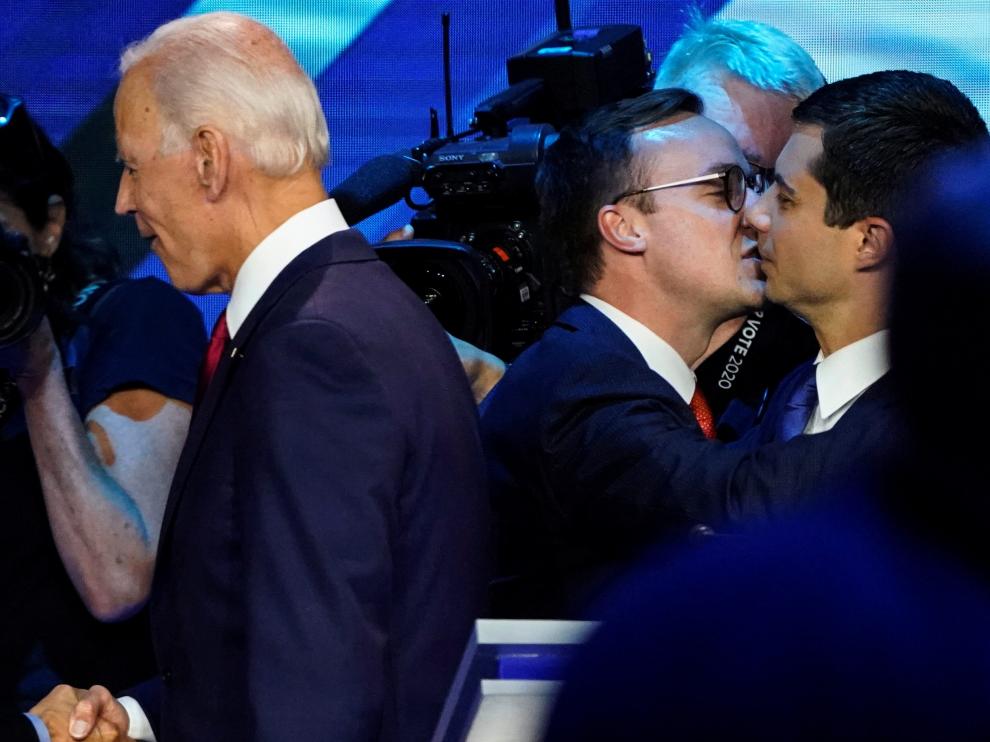 Pete Buttigieg recibe un beso de su marido Chasten con Joe Biden en primer término