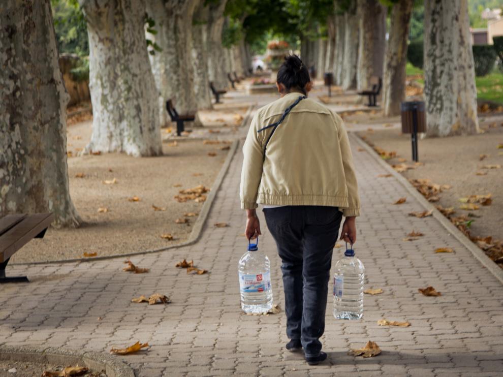Una mujer camina por Daroca con dos garrafas de agua.