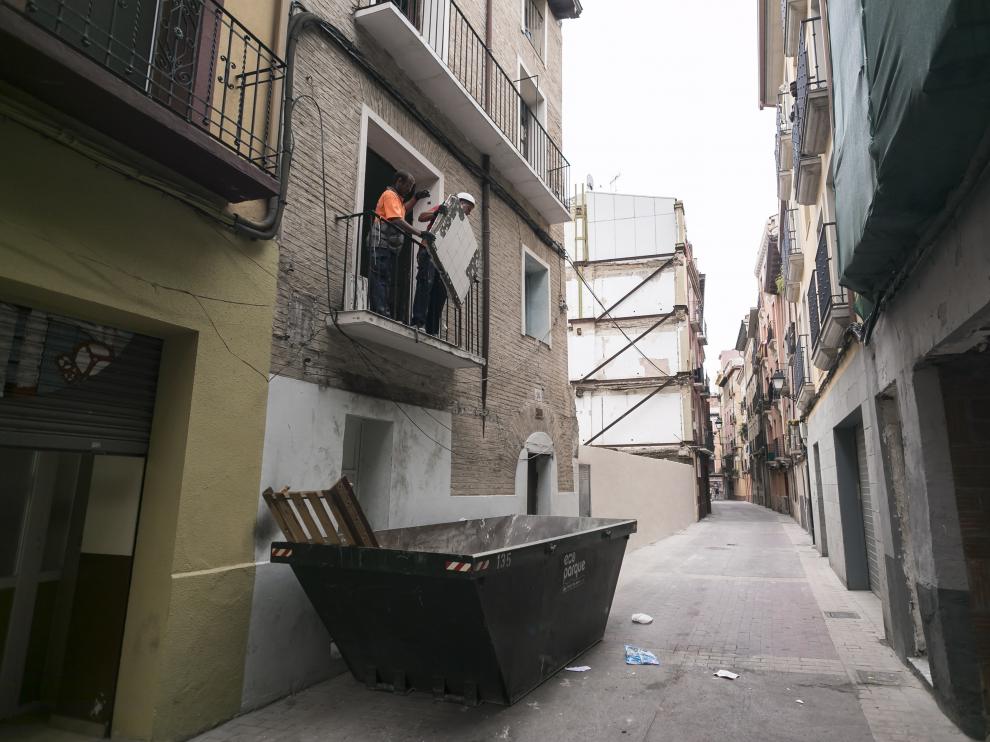 Un obrero arroja al contenedor basura y trastos de la casa okupa de Agustina de Aragón 26.