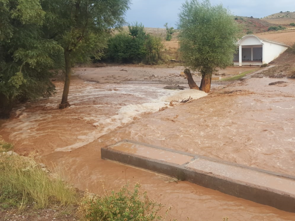 La rambla desbordada en Valdecebro y, al fondo, los lavaderos que han quedado llenos de barro.