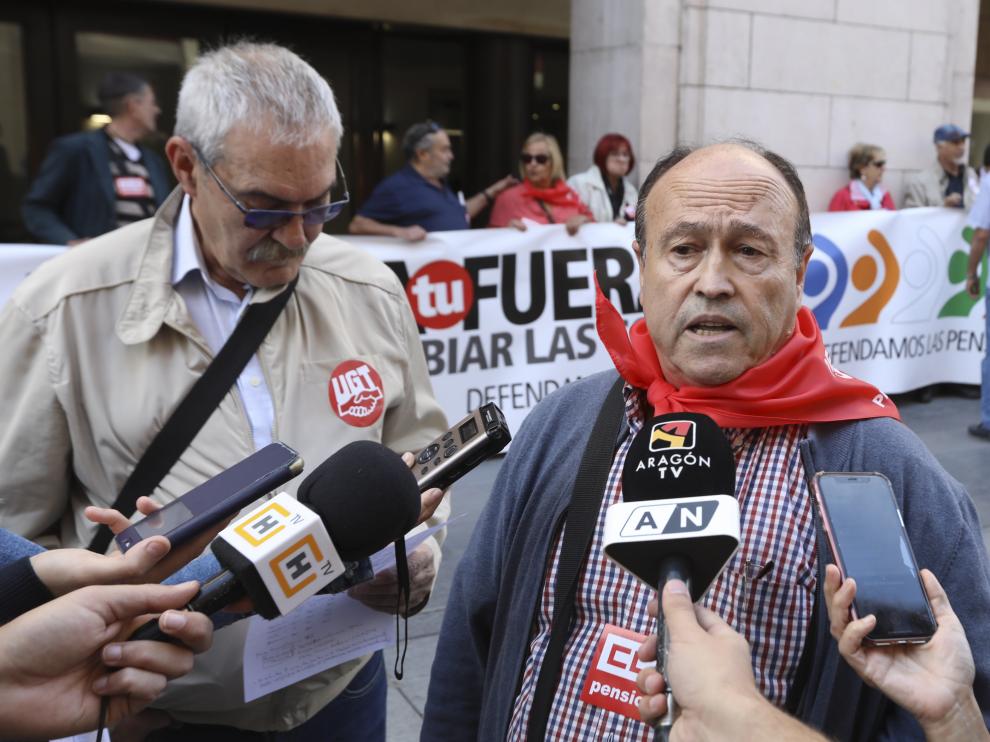 Los responsables de las federaciones de pensionistas de UGT y CC. OO. frente a la pancarta en los Porches de Galicia de Huesca.