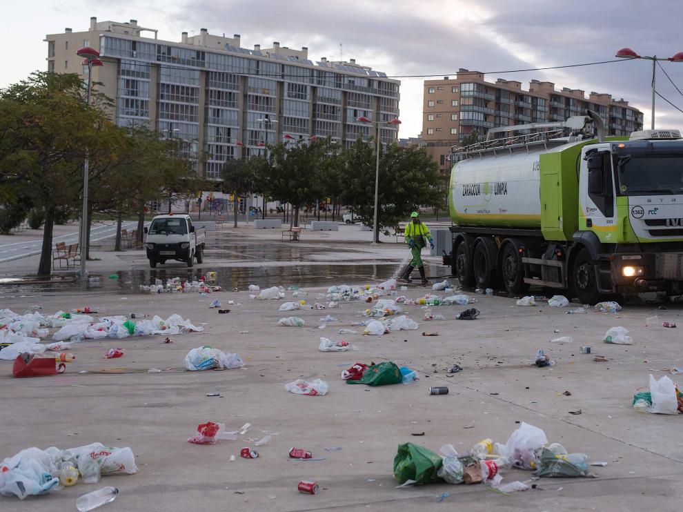 Operarios de FCC limpian a primera hora la enorme cantidad de basura que se acumula en el botellón de Valdespartera