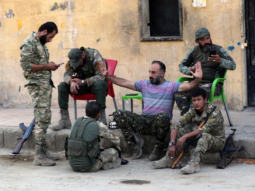 Rebeldes sirios apoyados por Turquía sentados cerca de un puesto fronterizo