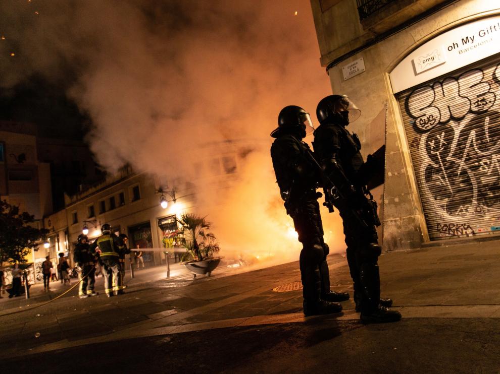 Los Mossos d'Esquadra controlan una calle del Raval mientras los bomberos apagan una barricada.