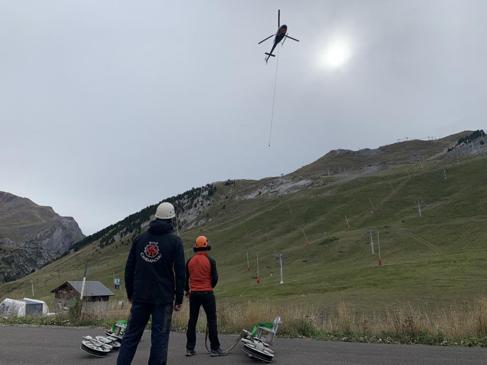 Un helicóptero traslada parte de las estructuras de los telesillas en la estación de Candanchú.