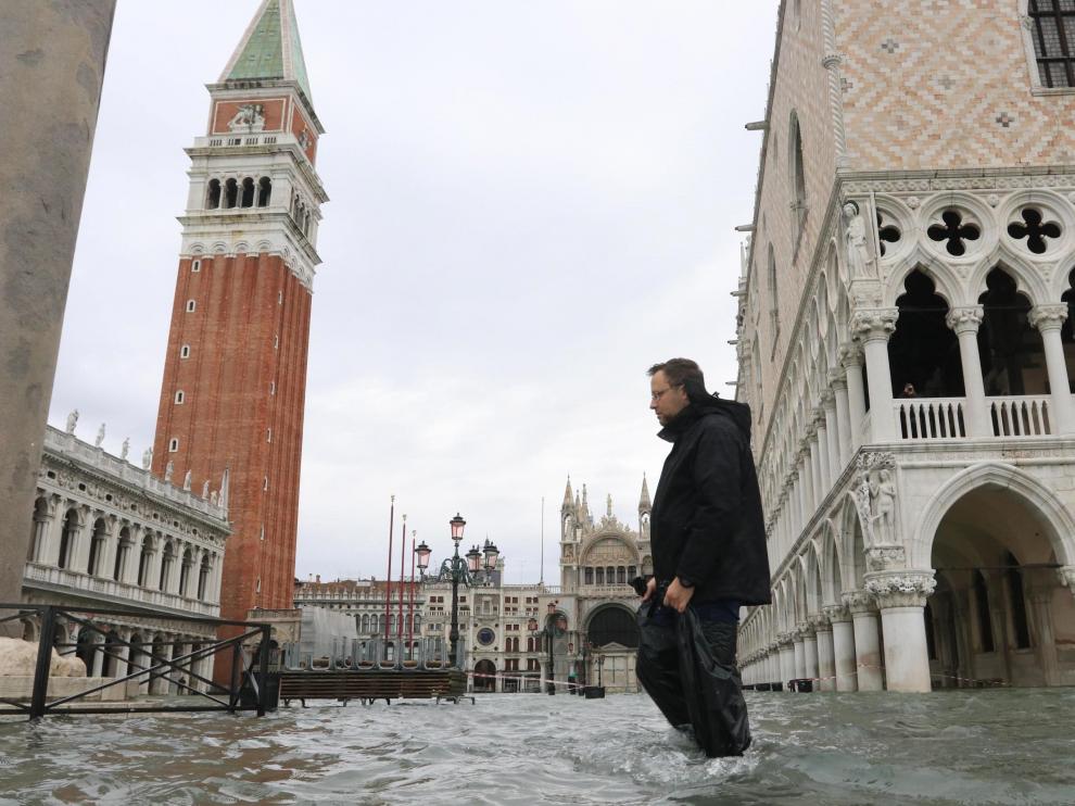 Un hombre camina por una inundada calle de Venecia.