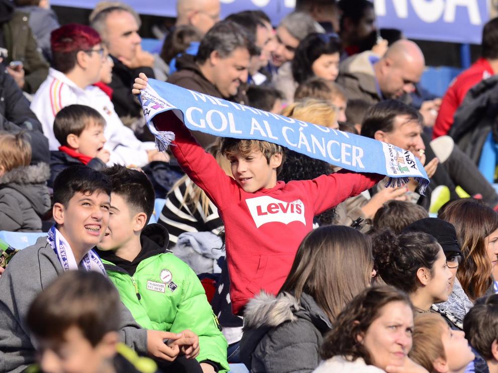 Un niño con una bufanda de Aspanoa en la que se puede leer el eslogan del partido benéfico.