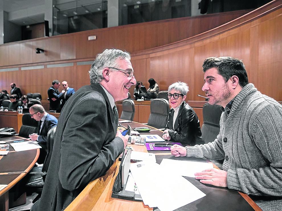 El consejero de Agricultura, Joaquín Olona, y Nacho Escartín (Podemos), este jueves en el pleno.