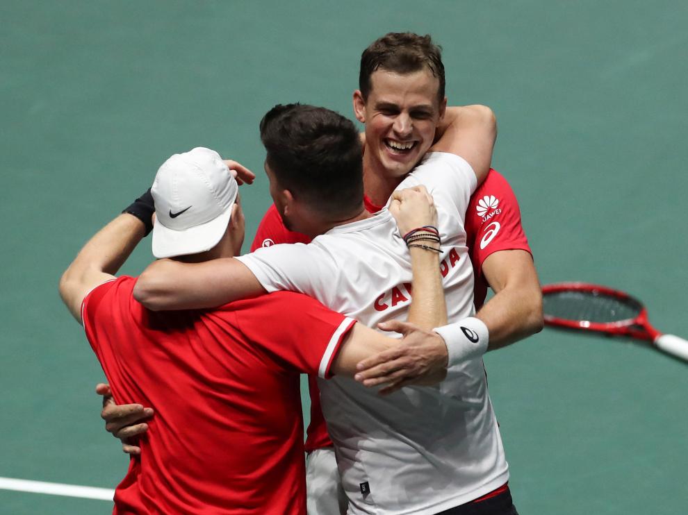 Los canadienses Denis Shapovalov (i) y Vasek Pospisil (d) celebran con su capitán, Frank Dancevic, su victoria ante los australianos John Peers y Jordan Thompson