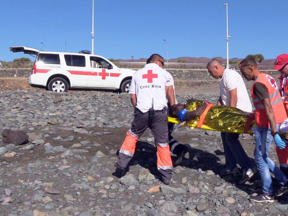 Varios bañistas atienden a un grupo de inmigrantes llegados en patera a Canarias.