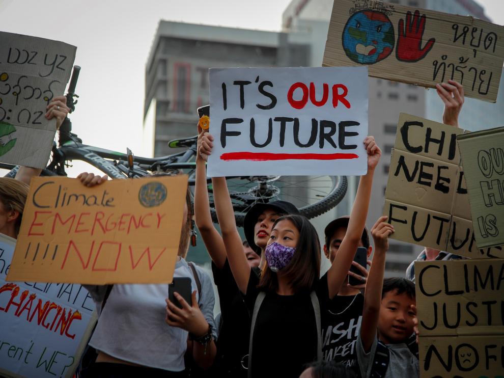 Varias personas sostienen pancartas con mensajes como "Este es nuestro futuro" durante una manifestación contra la crisis climática, este viernes a las afueras de un parque en Bangkok