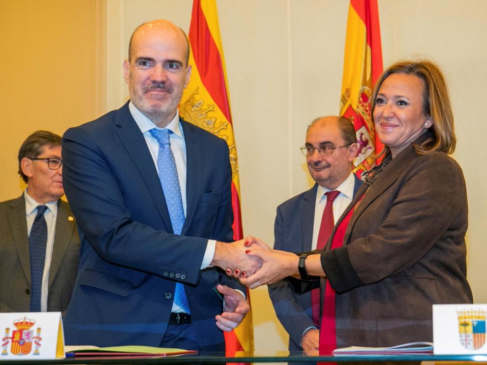 El secretario de Estado de Función Pública, José Antonio Benedicto (i), y la consejera de Presidencia, Mayte Pérez, se estrechan la mano tras la firma del convenio del Fite 2019 en presencia de Javier Lambán y Arturo Aliaga.