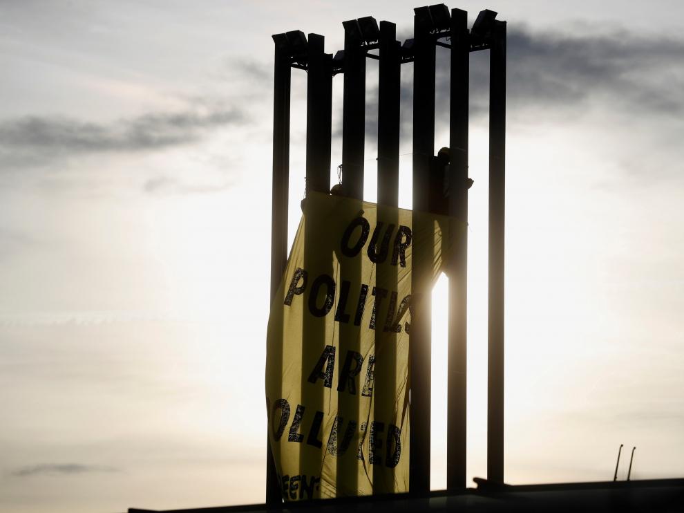Activistas de Greenpeace despliegan una pancarta en una torre de iluminación del recinto ferial Ifema.