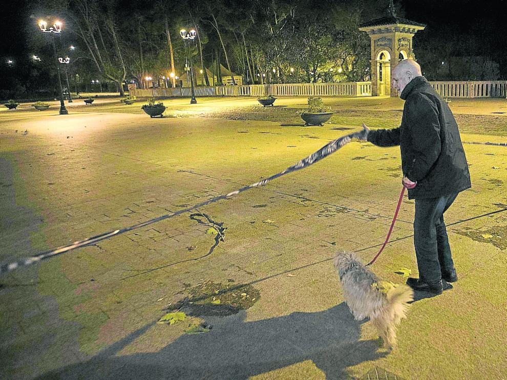 Un vecino levanta la cinta que impedía pasar al Parque Grande tras ser cerrado por la Policía.