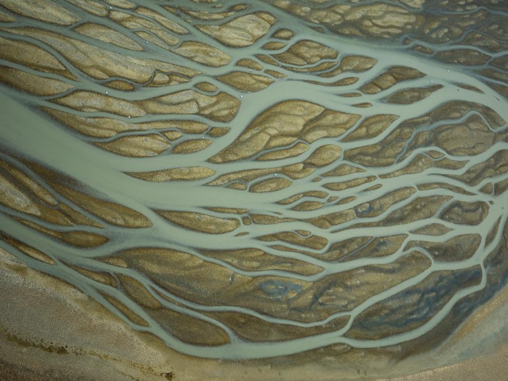 La confluencia de las corrientes hacia un único punto de desagüe distribuye el agua sobre la superficie limosa. Esta imagen de Veta la Palma, en el Espacio Natural de Doñana, muestra las formas de red dendrítica, que recuerdan las sinapsis neuronales.