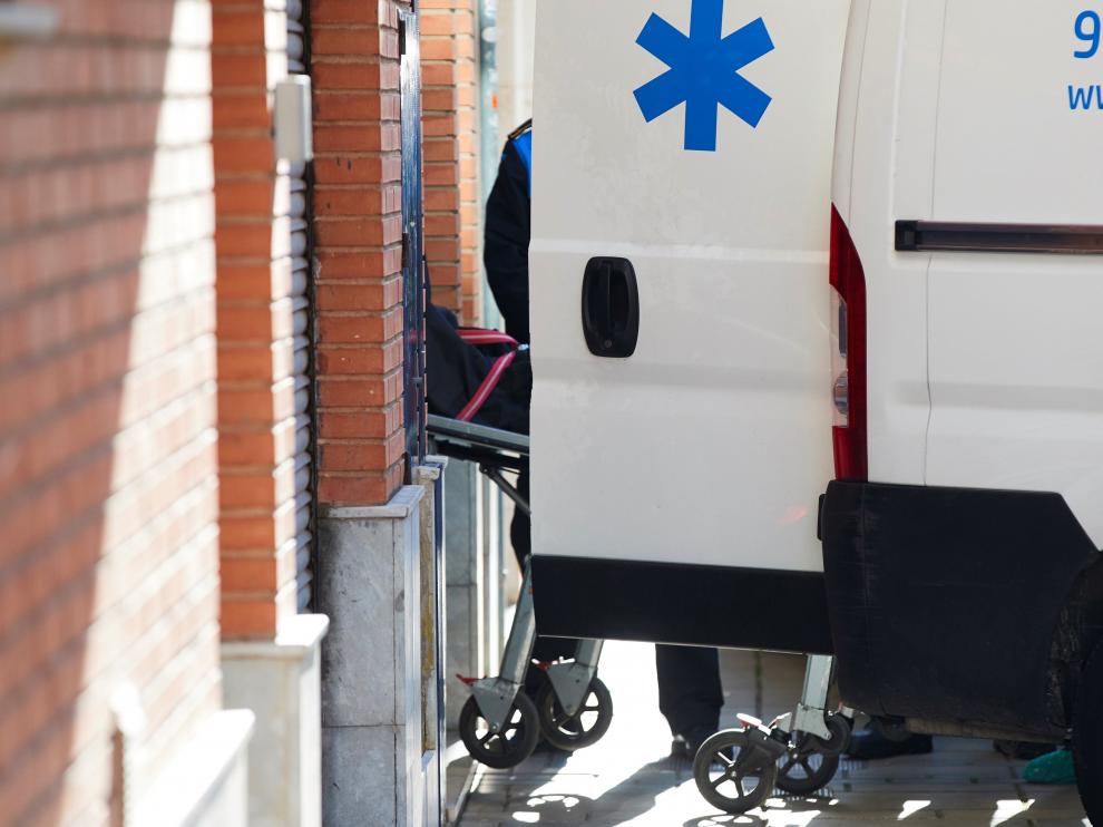 Miembros de los serviciones funerarios trasladan los cadáveres.