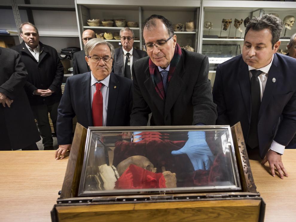 El antropólogo forenses Salvador Baena revisa el interior de la urna con los retos en la Facultad de Medicina, al lado del Justicia de Aragón, Ángel Dolado, y el secretario de la Hermandad Sangre de Cristo, Ricardo Marzo.