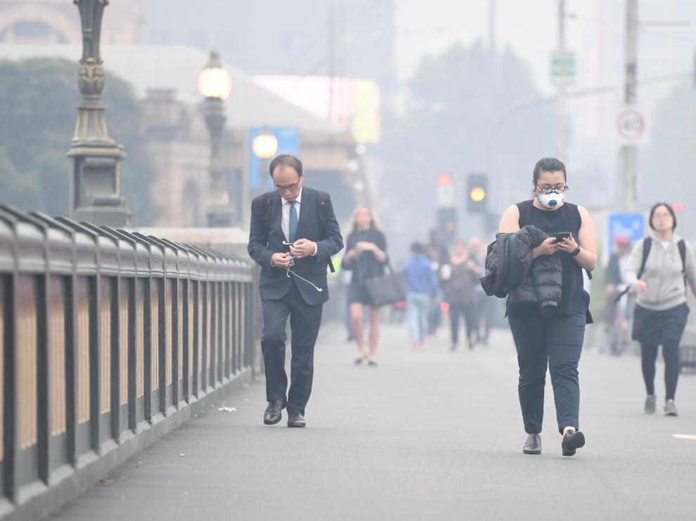 Melbourne (Australia), 13/01/2020.- Morning commuters are seen on Princes Bridge in front of the MCG amid smoke haze from bushfires in Melbourne, Australia, 14 January 2020. Smoke haze from the East Gippsland bushfires has drifted across Victoria reaching Melbourne prompting health warnings. (Incendio) EFE/EPA/ERIK ANDERSON AUSTRALIA AND NEW ZEALAND OUT Smoke haze over Melbourne