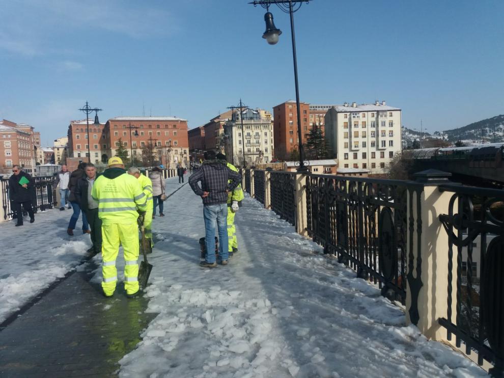 Operarios de Fomento retiran la nieve y el hielo que cubre el Viaducto Viejo de Teruel para evitar caídas.