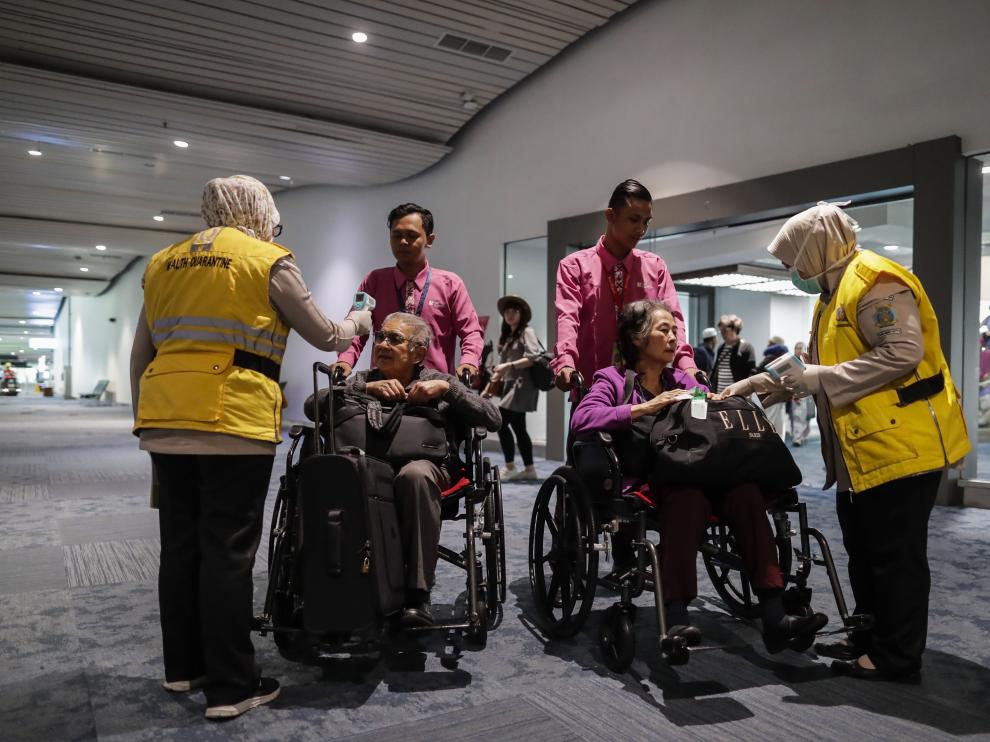 Personal de un aeropuerto internacional de Indonesia mide la temperatura a los pasajeros que llegan que llegan