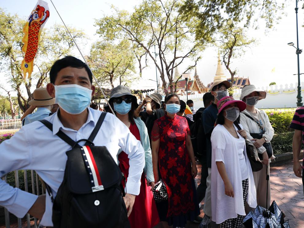 Turistas chinos llevan mascarillas durante la visita al Gran Palacio en Bangkok (Tailandia)