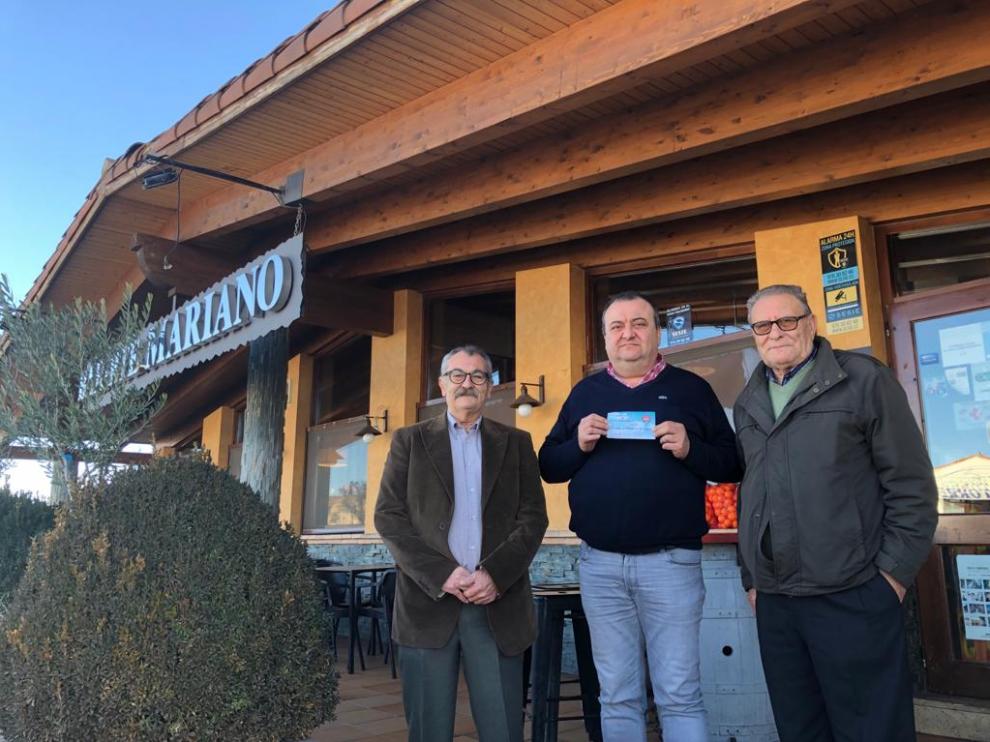 Juan Dolera (centro), José Jiménez (izda.) y Antonio Dormal (dcha.), enseñan el boleto premiado de la cesta de Calamocha a la entrada del restaurante Mariano.