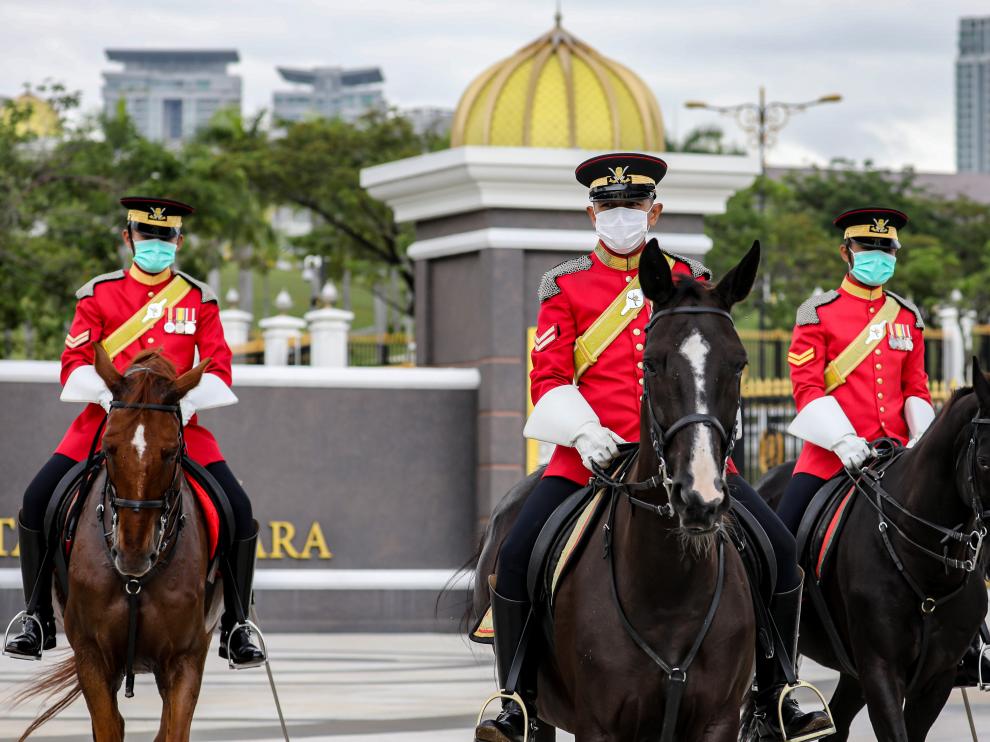 Los guardias reales de Malasia usan máscaras protectoras mientras hacen guardia afuera del Palacio Nacional, en Kuala Lumpur