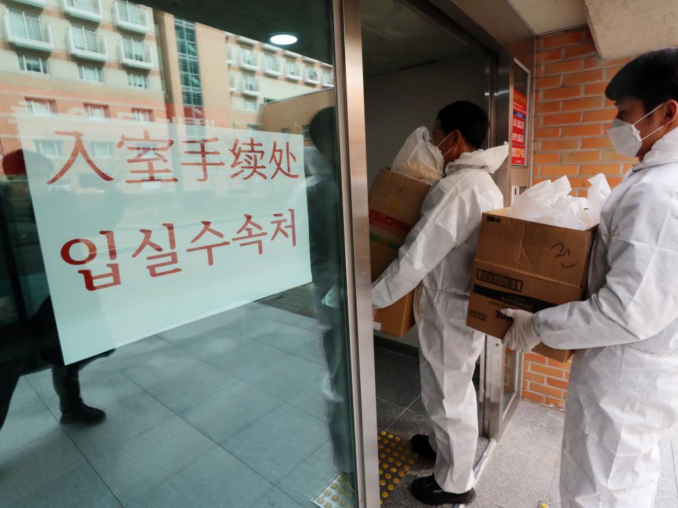 Empleados de la Universidad Nacional de Chunnam en Gwangju (Corea del Sur) se protegen para entregar comida a un grupo de estudiantes chinos que fueron aislados por el coronavirus