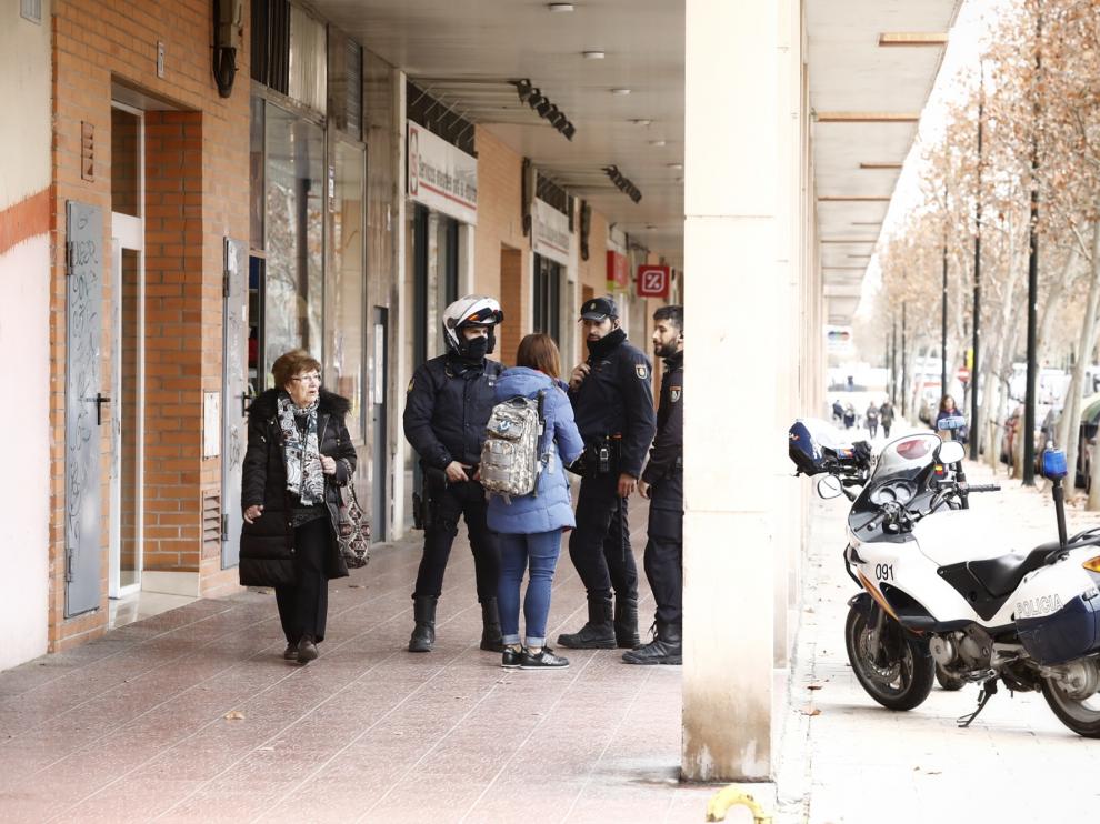 Una vecina pasa delante de la policía junto al portal del suceso.