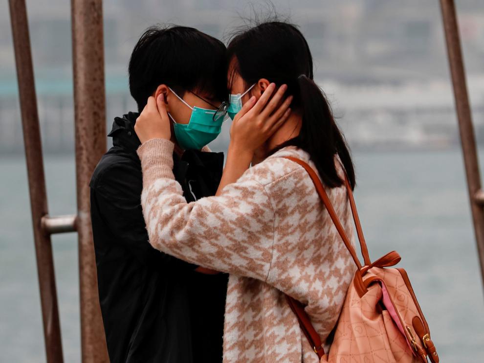 Una pareja con mascarilla se abraza en Hong Kong.