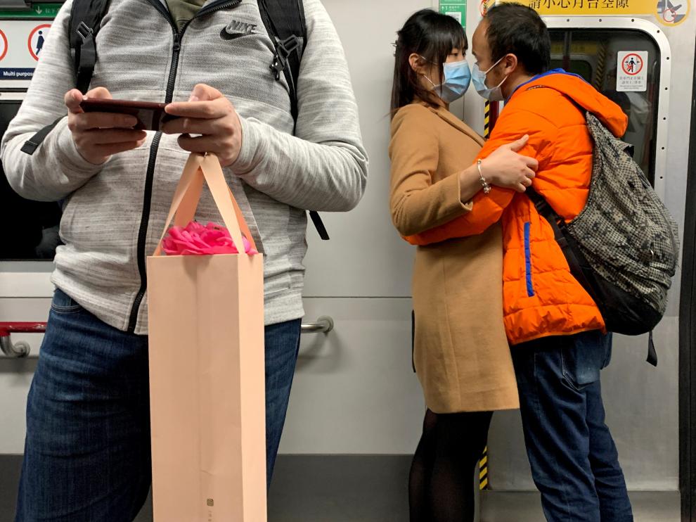 Una pareja con máscaras se abraza en un tren de Hong Kong
