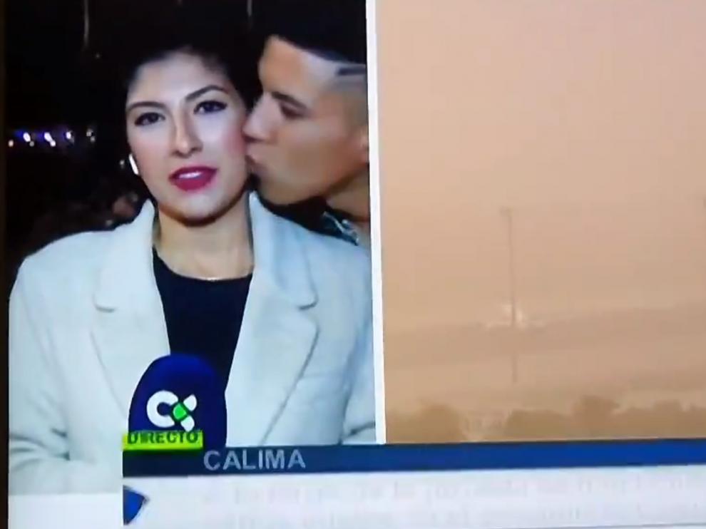 Momento en el que la periodista un besada por un viandante mientras hace un directo sobre la situación del aeropuerto de Lanzarote por la calima