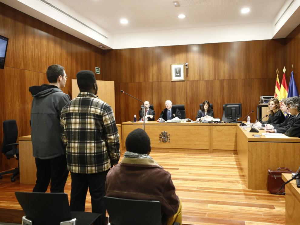 Los dos acusados, uno sentado y el otro, con la camisa a cuadros, de pie junto al intérprete de ghanés.