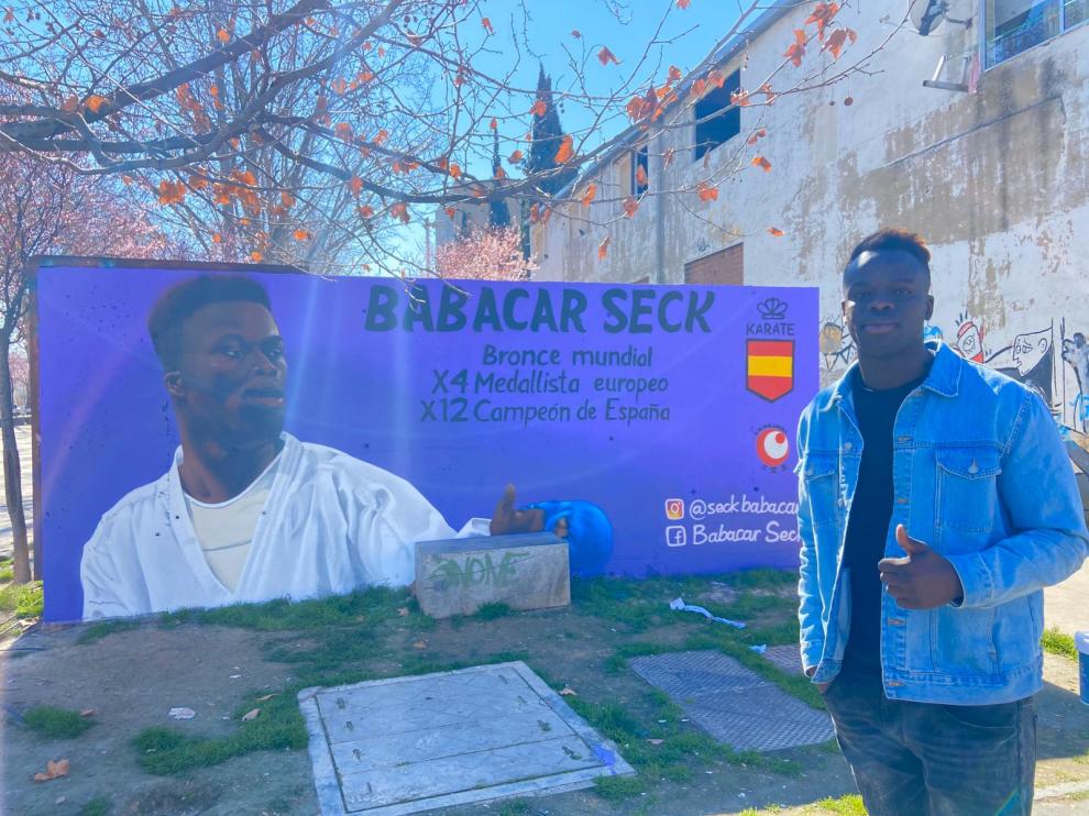 El karateca Babacar ante el grafiti que se muestra en el andador Antonio Leyva en el barrio Oliver