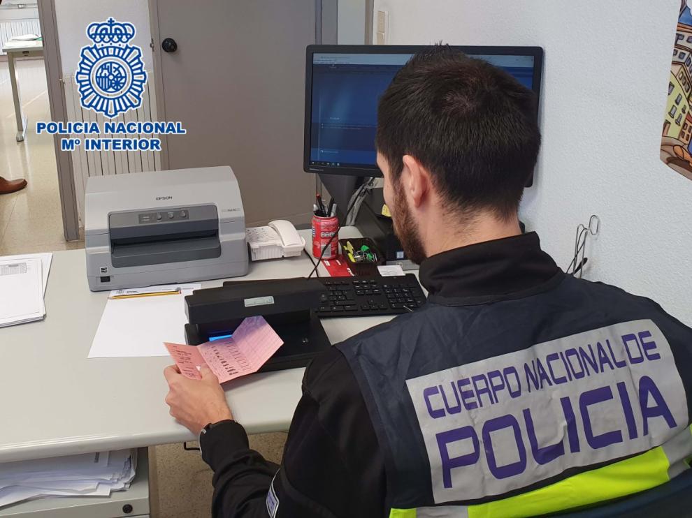 Un agente de la Policía Nacional comprueba la autenticidad del carnet de conducir del detenido.