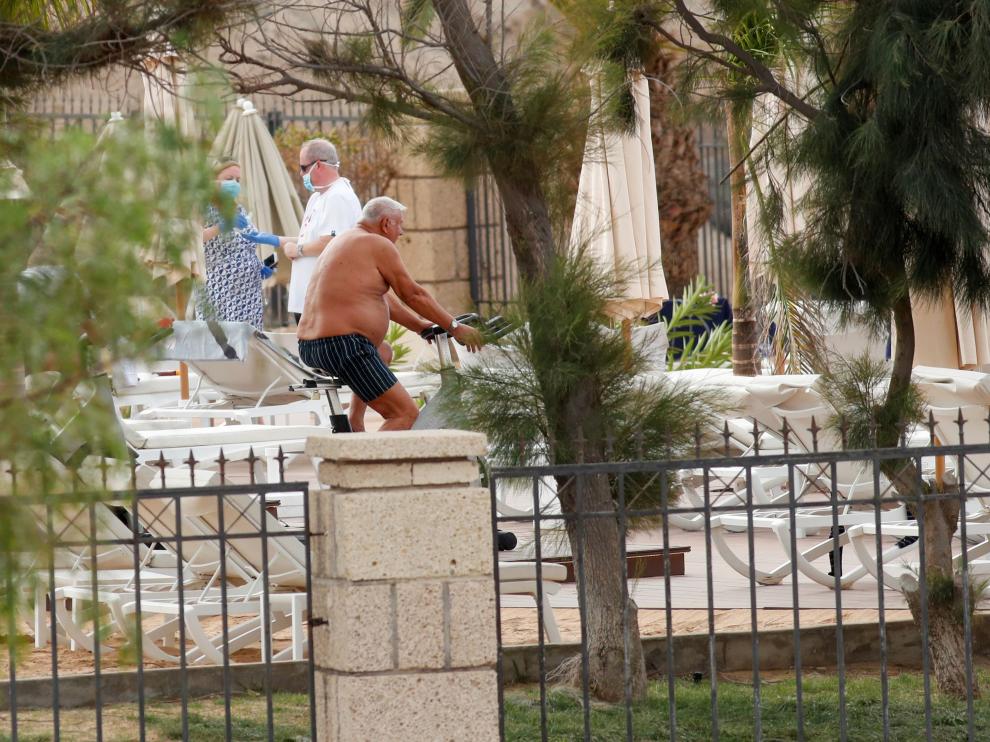 Tourists wearing face masks are seen next to the pool of H10 Costa Adeje Palace, which is on lockdown after cases of coronavirus have been detected there in Adeje