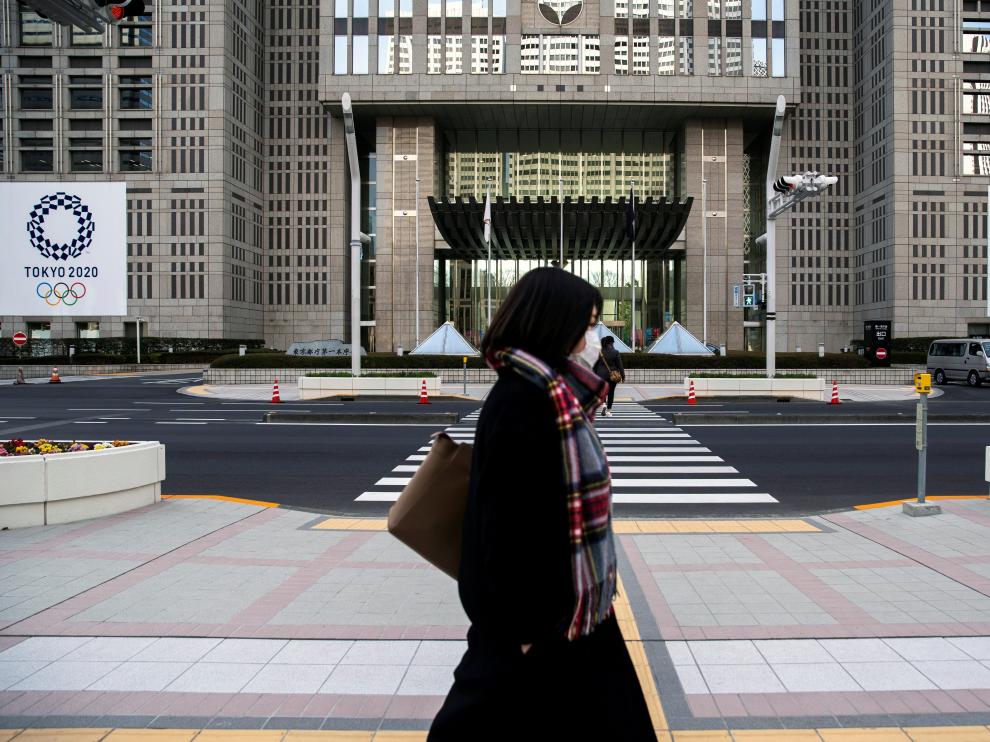 FILE PHOTO: A woman wearing a protective face mask, following an outbreak of the coronavirus, walks past banners of the upcoming Tokyo 2020 Olympic and Paralympic Games outside the Tokyo Metropolitan Government building in Tokyo