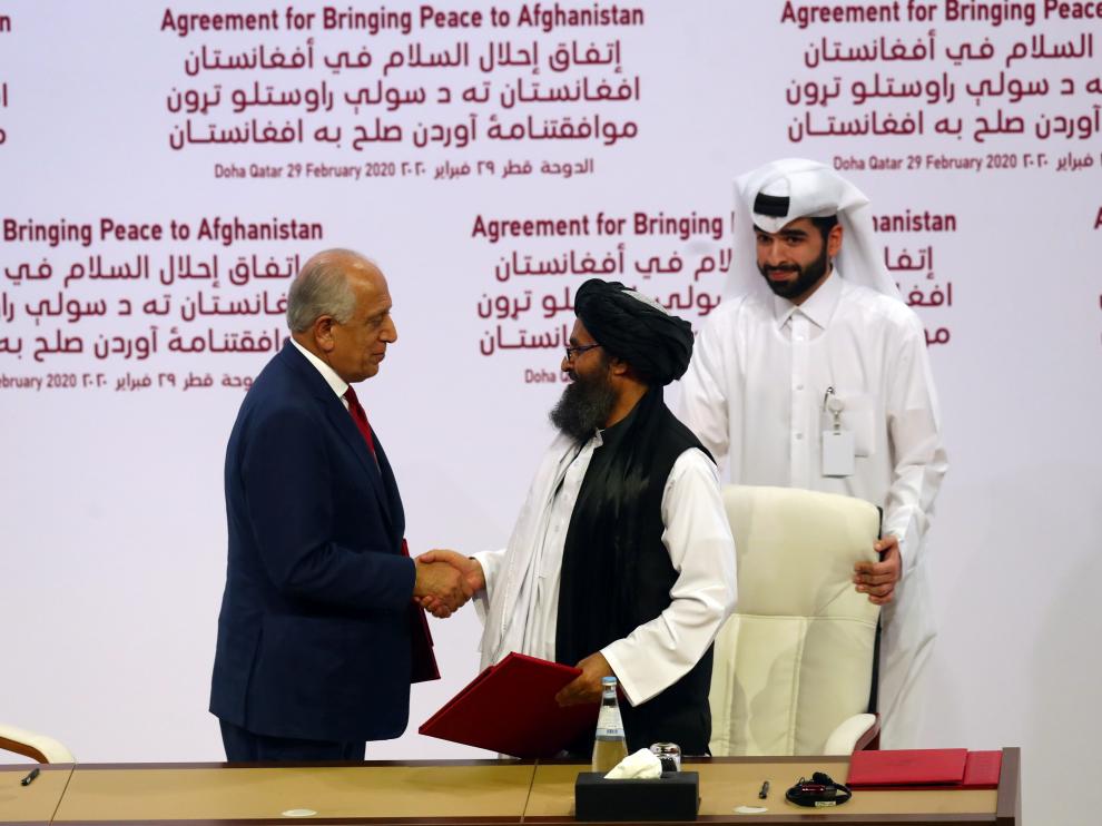 El mulá Abdul Ghani Baradar y Zalmay Khalilzad se estrechan la mano tras la firma del acuerdo.