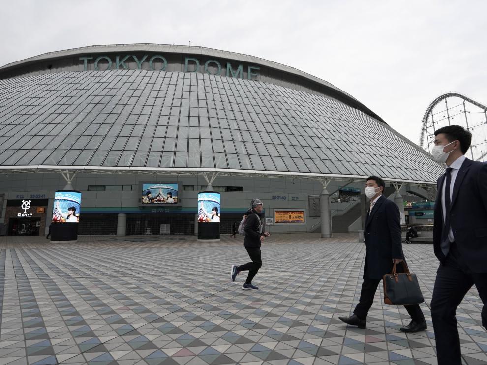 Ciudadanos pasan por delante del estadio olímpico de baloncesto en Tokio