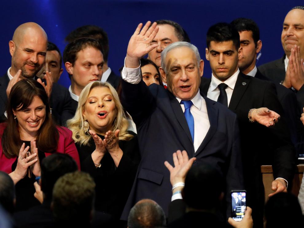 Israeli Prime Minister Benjamin Netanyahu stands next to his wife Sara as he waves to supporters following the announcement of exit polls in Israel's election at his Likud party headquarters in Tel Aviv
