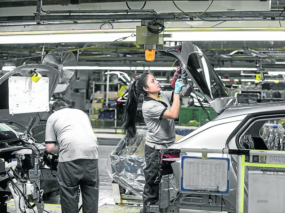Operarios trabajan en una cadena de montaje de la factoría zaragozana de Opel PSA.