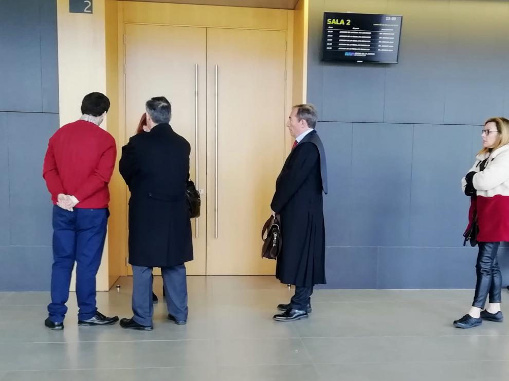 El acusado, junto a su abogada, y la hermana del fallecido, tras su letrado, este lunes en los juzgados.