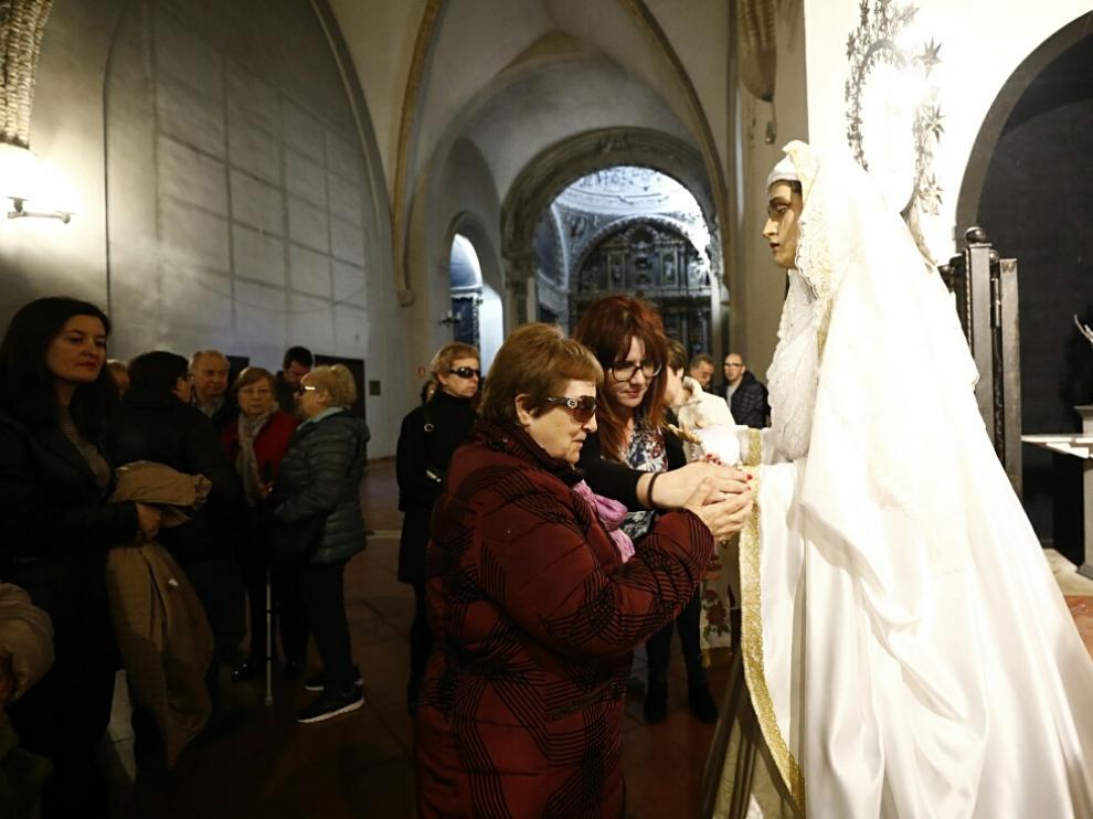 Una afiliada de la ONCE palpa a la Vuirgenla Virgen Blanca de la cofradía de El Silencio